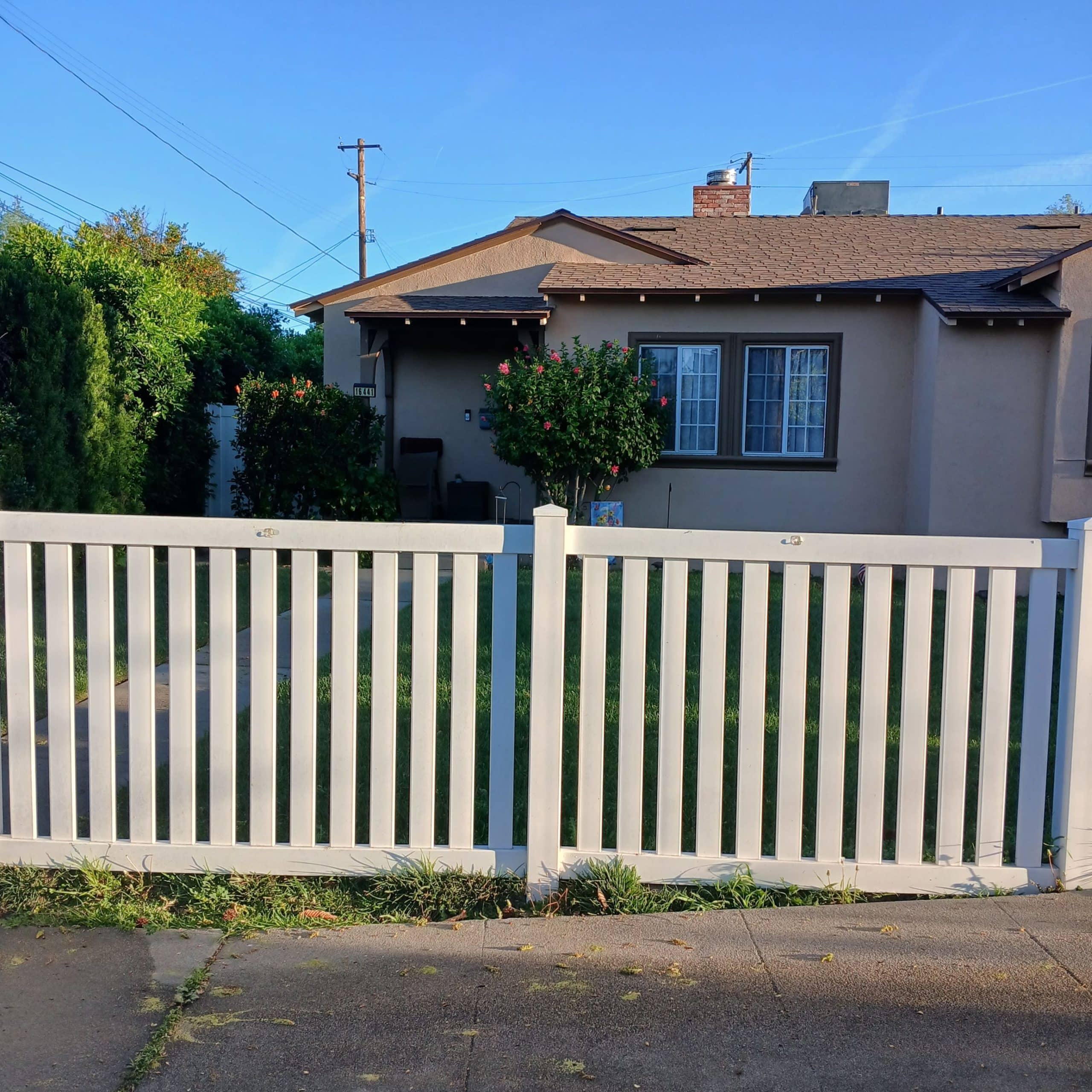 Single-story suburban house behind white picket fence