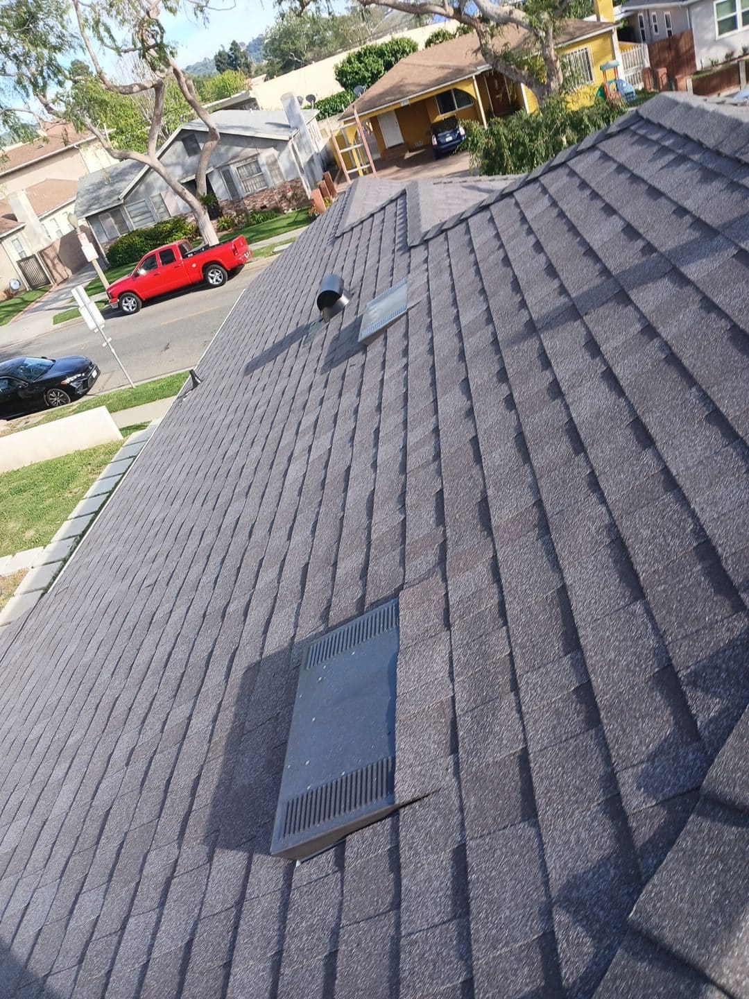 New dark grey asphalt shingle roof with two flat vents and pipe vent — Roof Replacement Inc