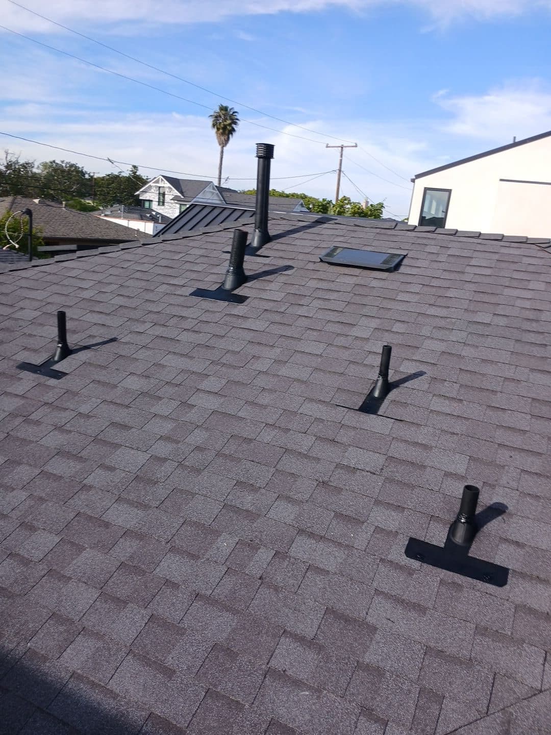 New asphalt shingle roof with multiple black pipe boots and skylight — Roof Replacement Inc
