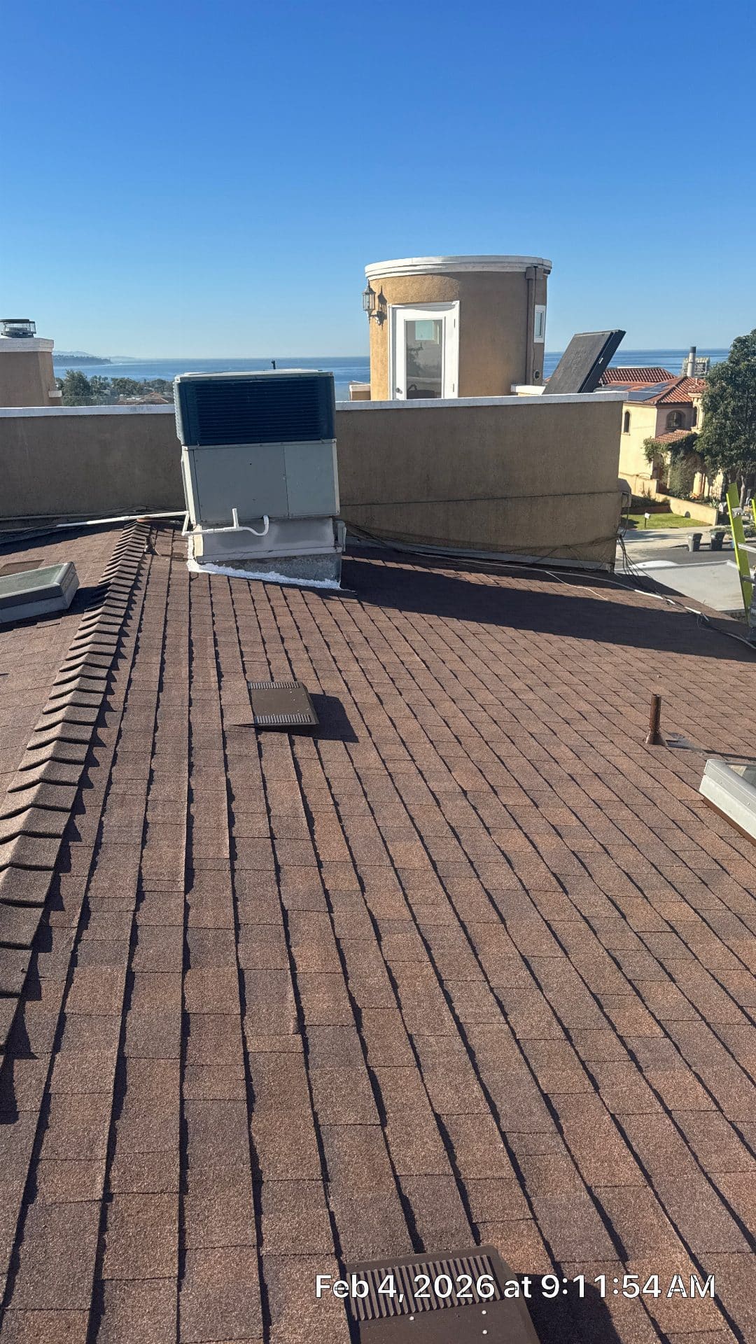 Brown asphalt shingle roof with vents, skylight, and rooftop HVAC unit — Roof Replacement Inc