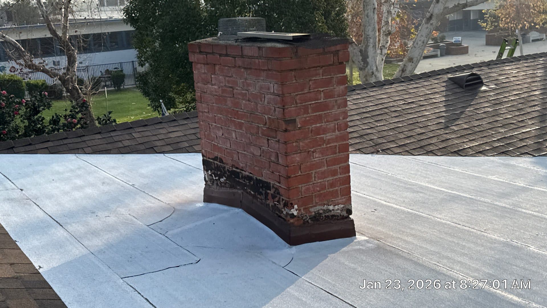 Brick chimney on flat white roof with deteriorated base flashing in Burbank | Roof Replacement Inc brick chimney on flat white roof with deteriorated base flashing — Burbank — Roof Replacement Inc