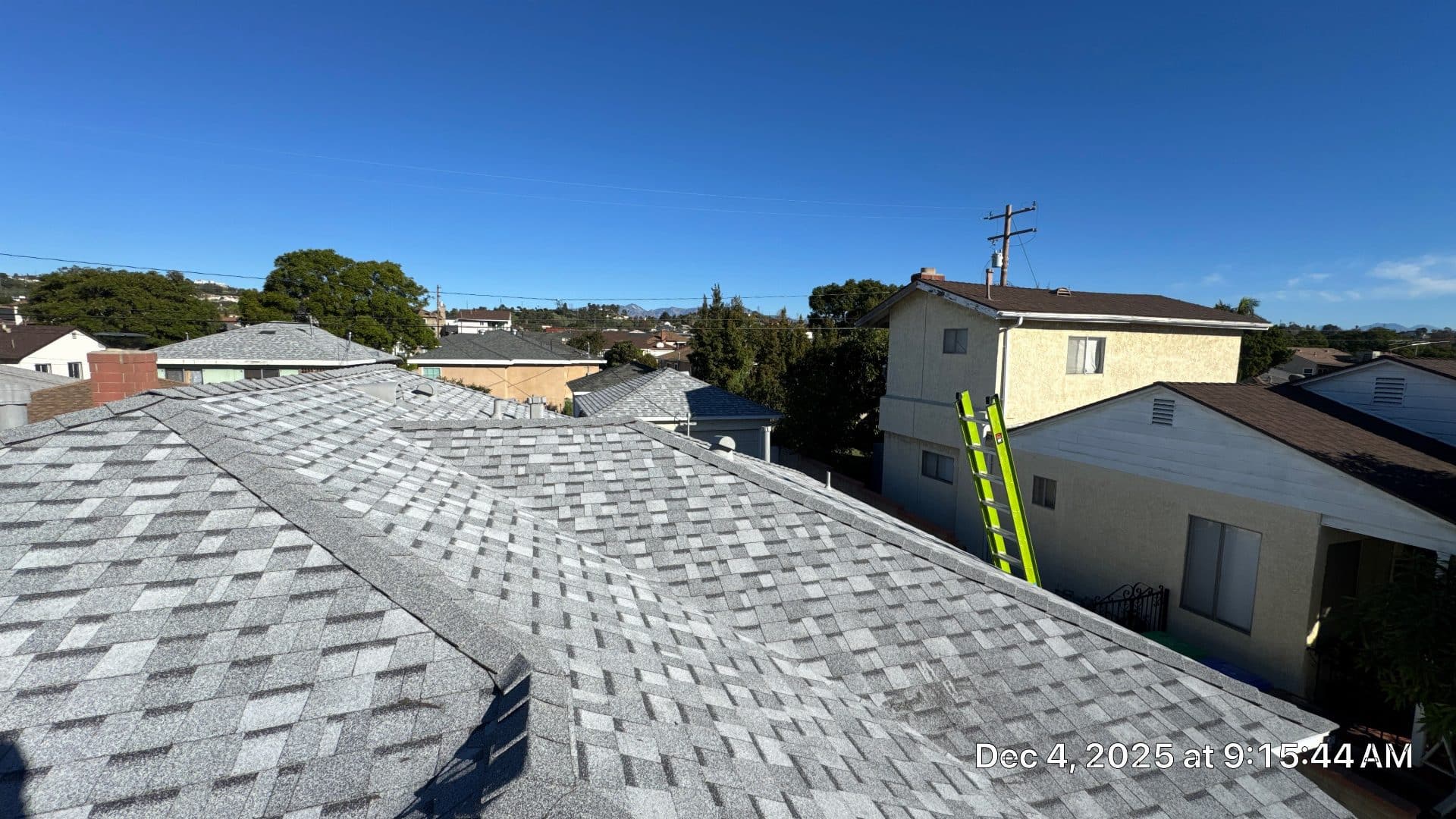 Gray asphalt shingle roof with green ladder leaning on eave | Roof Replacement Inc Gray asphalt shingle roof with green ladder leaning on eave — Roof Replacement Inc
