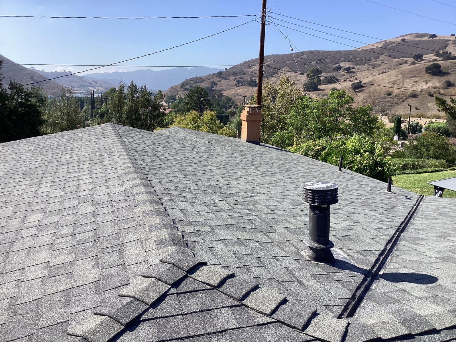 Gray asphalt shingle roof with black plumbing vent and brick chimney in Calabasas | Roof Replacement Inc gray asphalt shingle roof with black plumbing vent and brick chimney — Calabasas — Roof Replacement Inc