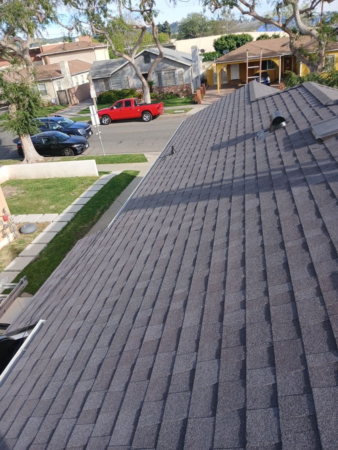 New dark gray asphalt shingle roof with vent pipe and ridge cap — Roof Replacement Inc