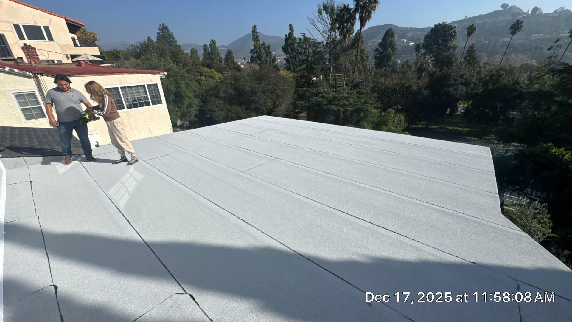 Two workers inspecting completed white flat roof membrane — Glendale — Roof Replacement Inc
