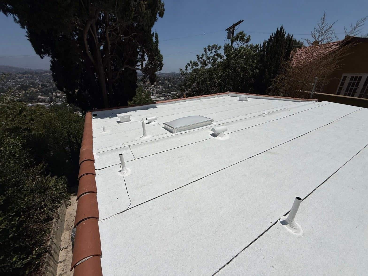 Flat roof showing contrast between aged modified bitumen membrane and freshly applied white silicone coating
